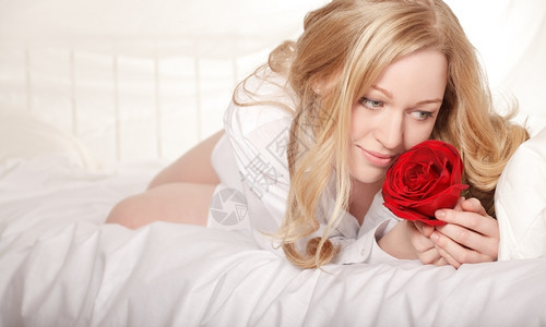 水平的穿着红玫瑰睡在床上的漂亮女孩枕头花图片