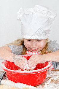 筛孩子快乐的女在厨师角帽打破鸡蛋在一个碗图片