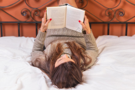 文学卧室躺在床上的妇女读一本书躺在床上的妇女读一本书图馆图片