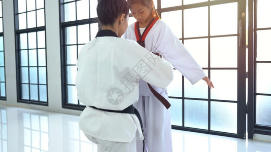 柔术训练员帮助亚洲女孩调整训练服装以适应泰拳道权讲师图片