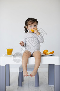 乐趣团结坐在桌边吃橙子的女婴厨房图片