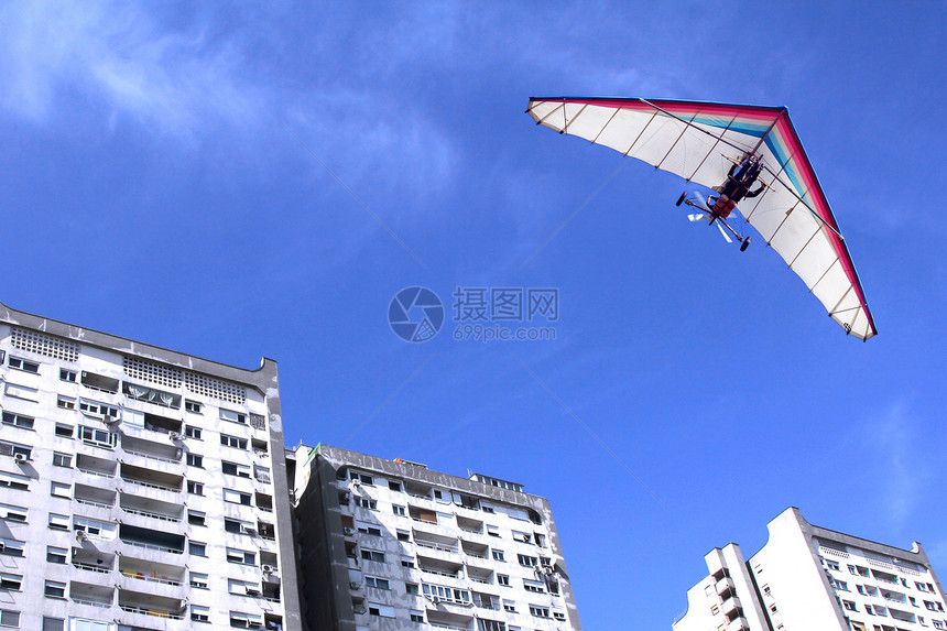 超过摩托滑翔机在城市住宅楼上飞翔越该市的住宅楼天空假期图片