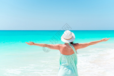 快乐的女子在海滩上放松后看着身帽子的女孩在海边人躺滩上享受暑假看着大海洋水休息背景图片