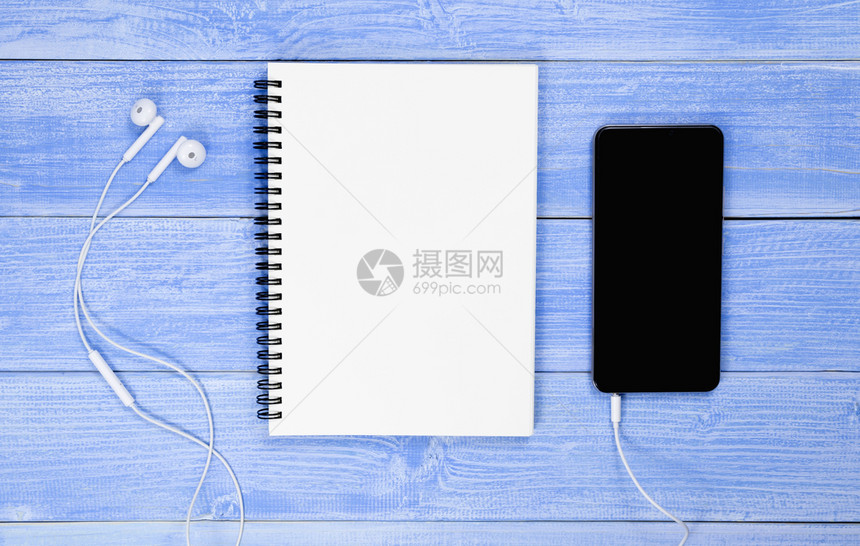 空白的信息复制桌子顶部视图上有蓝色笔记本电话和耳头板设计用在笔记本上注图片