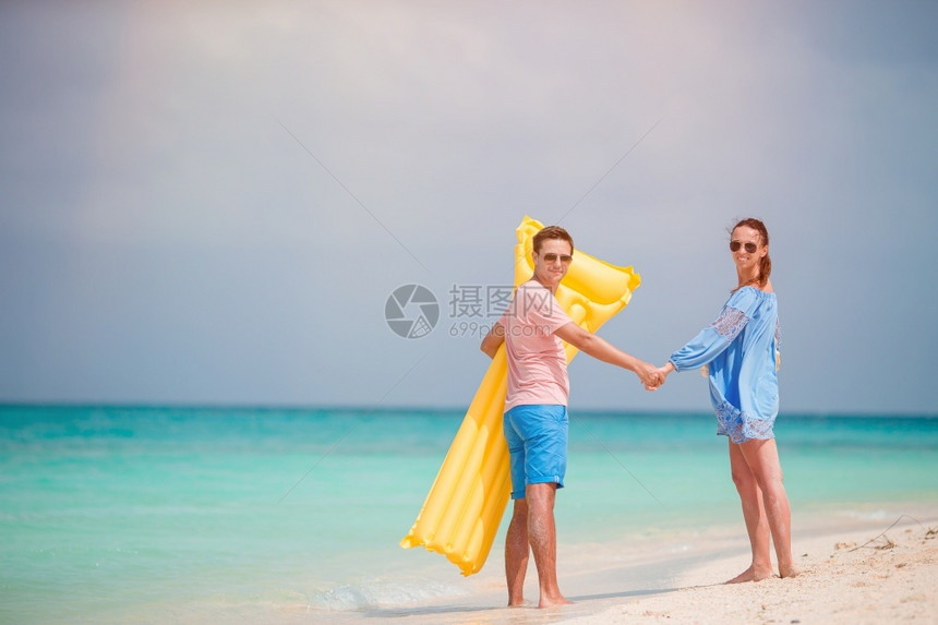 年轻情侣在沙滩上散步形象图片