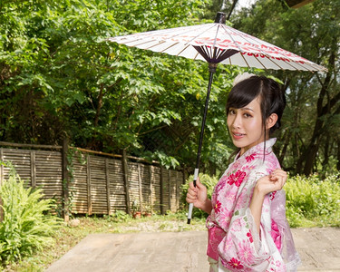 女和服的亚洲人在日本风格的花园里拿着雨伞戏服趋势图片