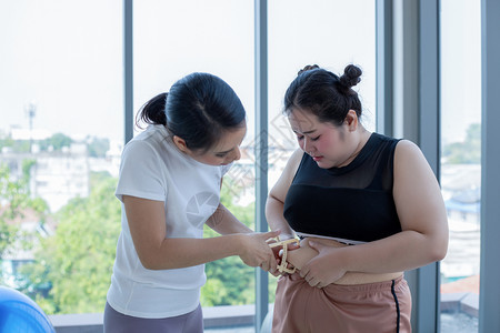 年轻女训练员测量妇女腰围背景图片