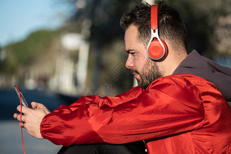 男细胞参加运动的年轻人穿服用耳机听音乐电子的图片