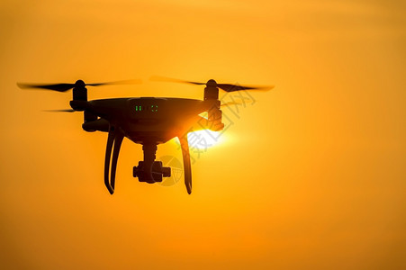 摄影螺旋桨户外日落时使用摄像头飞行的无人机Silhouette图片