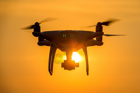 照片日落时使用摄像头飞行的无人机Silhouette螺旋桨转子图片