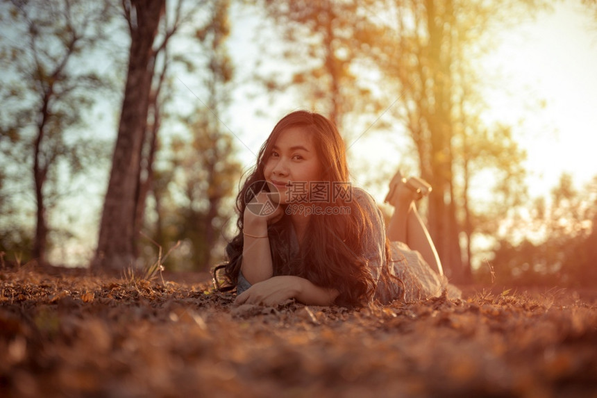 年轻的亚洲女人在秋天公园的摄像头面前摆姿势可爱的微笑相机图片
