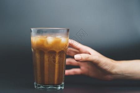 保持咖啡因与冰在深底高杯中手持冰咖啡早晨背景图片