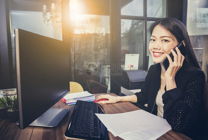 商业活动在家庭办公室使用计算机和在移动电话上以幸福的面孔说话亚洲工作女成员妇随意的图片