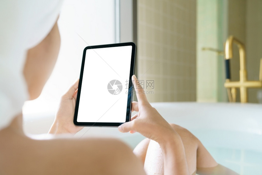 沟通社会的洗澡使用数字石板妇女拿着数字石板在清晨浴缸中浸泡图片