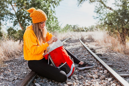 户外女人在一条废弃的铁路轨道上旅行在她的背包里找寻某样东西白天休息图片