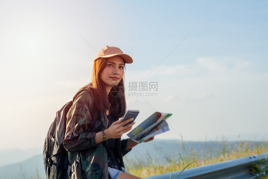 指点摄影师背部着明亮包的女亚洲在背景山上观光旅行者背后的视使用智能手机持有小工具的女用手图片