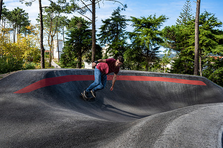 溜冰娱乐在阳光明媚的日子里滑板机在水泵跑道公园练习鞋图片