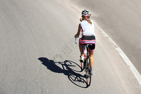 自行车骑的女运动员在开阔的道路上沥青移动巷道图片