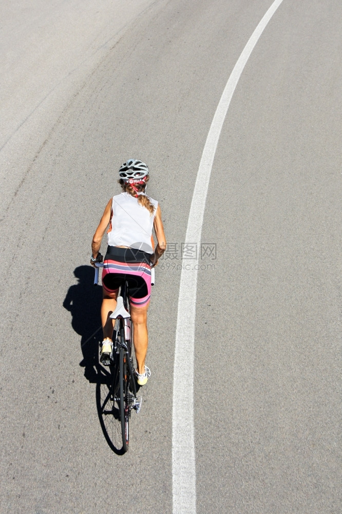 快速地车轮臭鼬自行骑的女运动员在开阔的道路上图片