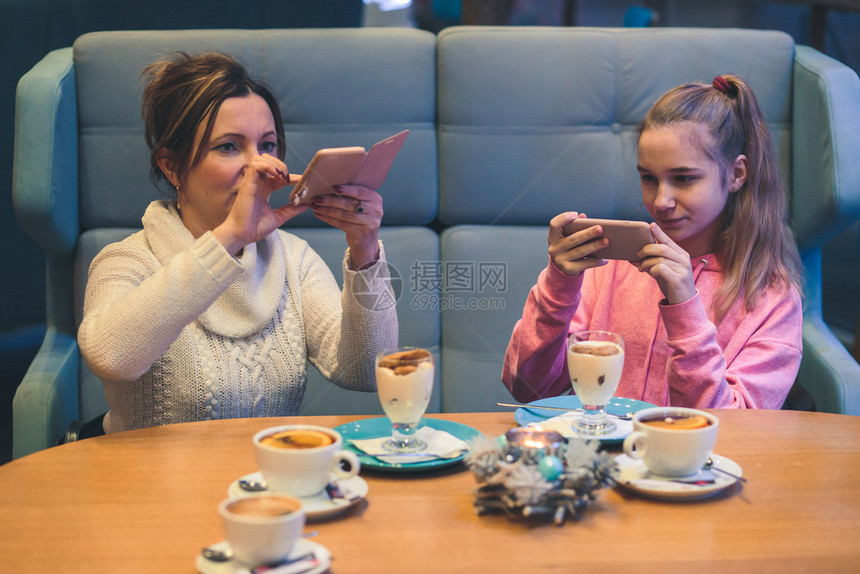 青年相片社会的女在咖啡店拍摄甜点的照片使用智能手机相的人Candid真实时刻情况图片