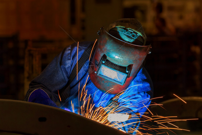 在工厂中焊接汽车部件的防罩工人与汽车部分焊接使固定连安全图片