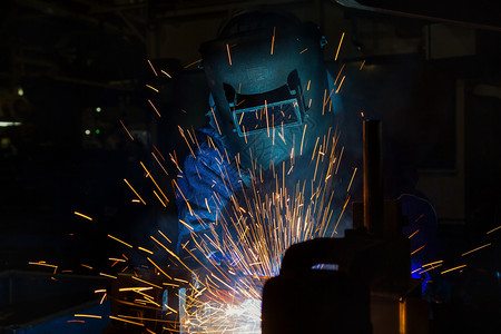工作在厂中焊接汽车部件的防罩工人与汽车部分焊接工业的面具图片