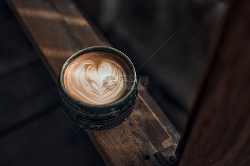 在木制桌上有选择焦点杯热拿铁艺术咖啡重点是在木制上热拿铁艺术咖啡上方的白泡沫可巧克力口图片
