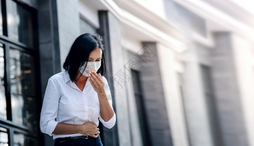喉箍肺癌或科罗纳概念商业妇女在城镇市的传播中用医疗面具咳嗽女预防上市背景