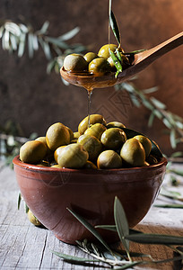 以木勺为橄榄在碗上浇油生的植物津乐道高清图片