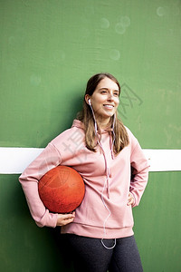 女士长头发的年轻女孩拿着篮球挡绿墙玩女运动员图片