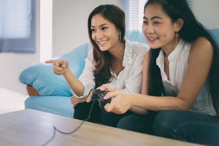 团体游戏玩家有两个竞争力的女朋友在玩电子游戏家开心快乐地欢愉沙发图片