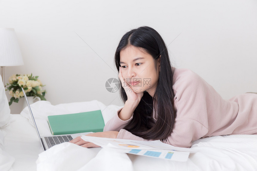 采用打字亚洲人在床上使用笔记本电脑的亚洲妇女青少年在家中使用计算机图片
