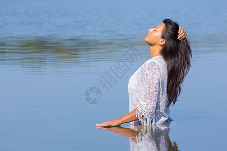 夏天黑色的舍内维尔身着长黑头发和白衣服的哥伦比亚妇女站在天然湖中背景图片