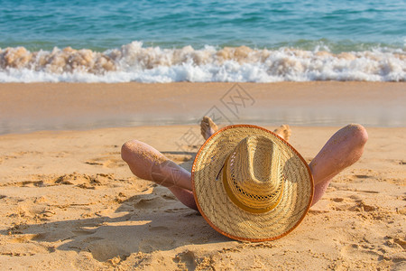 海洋浪潮年轻的戴帽子躺在海滨的年轻达奇人图片