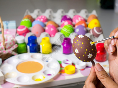 复活节妇女画在东方鸡蛋上的彩画在东方节的鸡蛋上美艺术作品以优美的方式与刷子一起绘制各种颜色的彩蛋紫粉节日背景图片