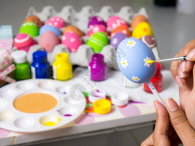 复制夏天活节妇女画在东方鸡蛋上的彩画在东方节的鸡蛋上美艺术作品以优美的方式与刷子一起绘制各种颜色的彩蛋粉背景图片