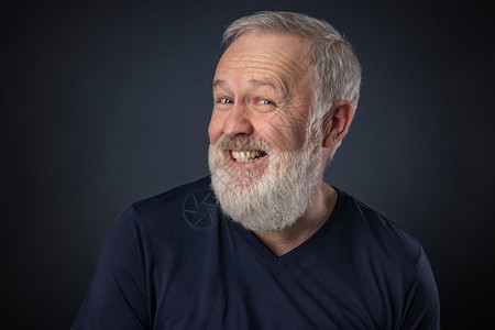 长着灰胡子的老人肖像蓝底脸色灰胡子玩耍和假装笑男积极的灰色背景