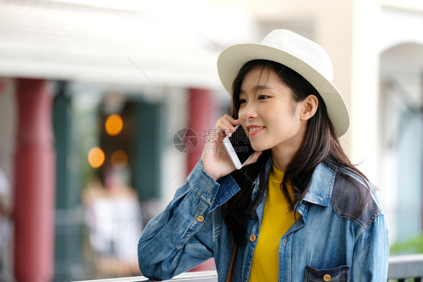 帽子天在城市户外使用手机的年轻女在城市生活方式中的电话用户城市妇女吸引人的图片