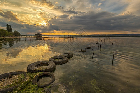 风景优美湖边丽的日落水里和旧轮胎有渔网场景海图片