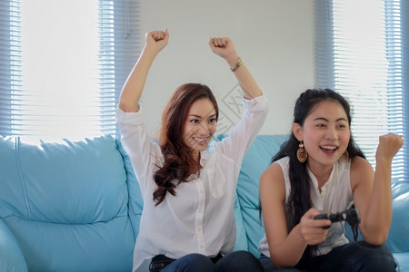 沙发快乐的朋友们有两个竞争力的女朋友在玩电子游戏家开心快乐地欢愉图片