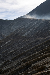 健壮的徒步旅行者在火山口上走通过烟雾和胆大沃克抽图片