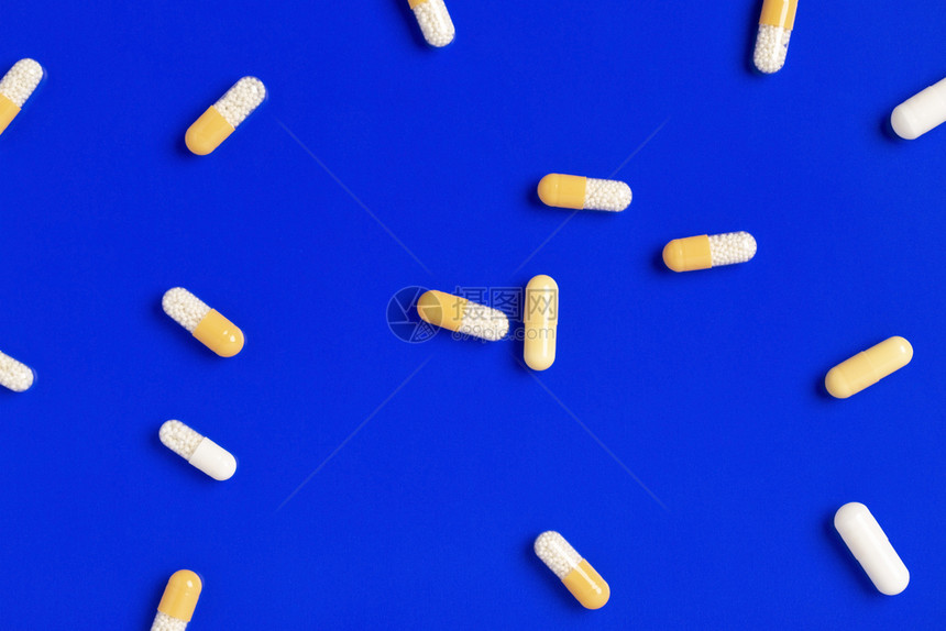 放生病的反抗单色背景上的彩药丸胶囊蓝背景上的黄药丸图片