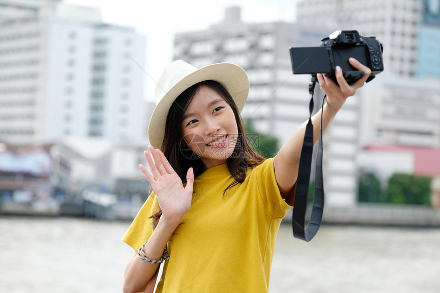 移动的时髦使用相机在城市自拍户外背景女自拍带有技术旅行和生活方式概念的户外人士以随意方式从事临时工作的年轻可爱亚洲女街道图片