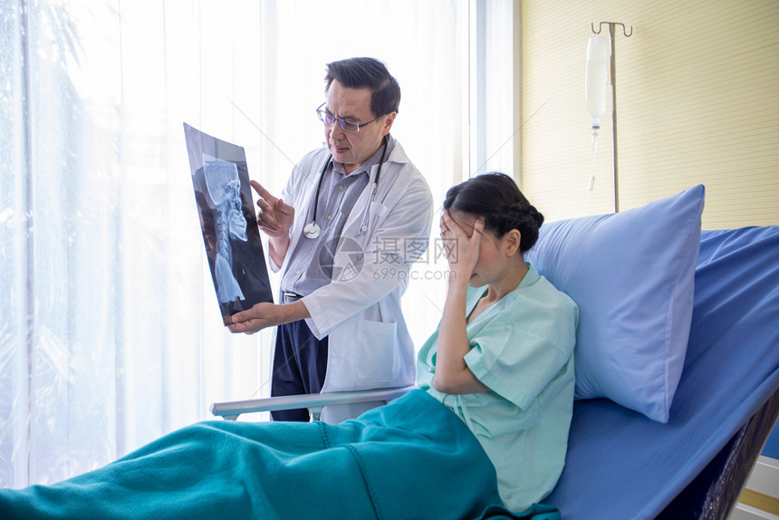 专家医生正在向躺院床上的一位女病人解释脑X光检查结果图片