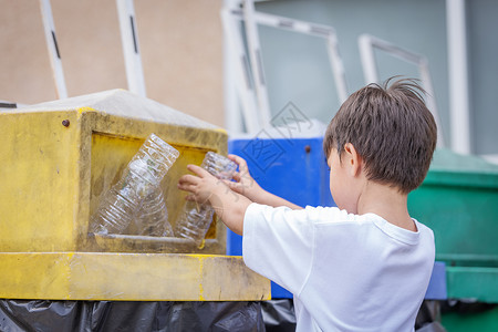 垃圾入篓浪费空的保持儿童收集塑料水瓶和将空扔入对垃圾无害的理念中儿童收集塑料水瓶和把空扔进垃圾桶背景
