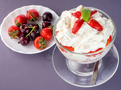 可口食物红色的玻璃碗草莓生奶油和浆果背景是碟子草莓生奶油玻璃碗浆果图片