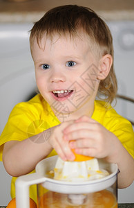 美丽富有表现力的可爱穿黄色背心从橙子里拔出果汁的孩子图片