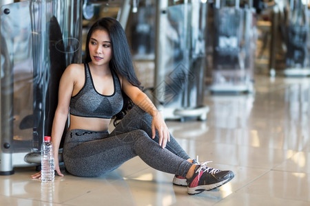 休息年轻的内部参加体操室内健身俱乐部和的亚洲妇女用一瓶水喝运动会图片