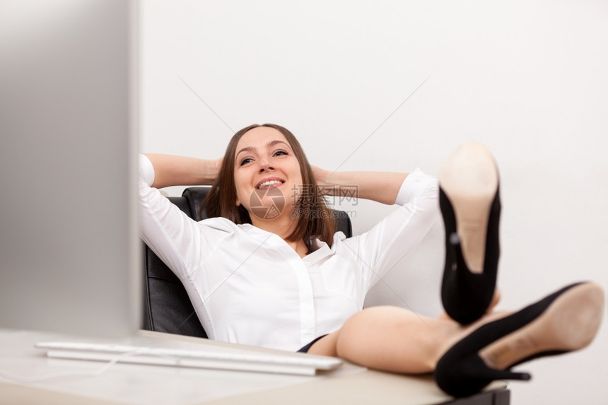 休息经理工作照片轻松的女商人在办公桌前有双腿图片
