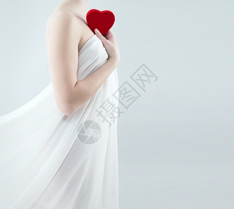 美丽浪漫身穿白色窗帘的美女将红心抱在肩膀上色的图片